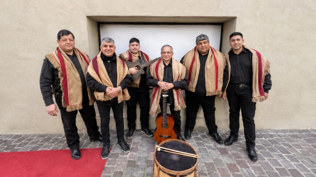 Los seis integrantes de Los Zafreros posan con ponchos, guitarras y bombo legüero frente a una pared.