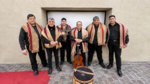 Los integrantes de Los Zafreros posan con ponchos, guitarras y bombo legüero frente a una pared.