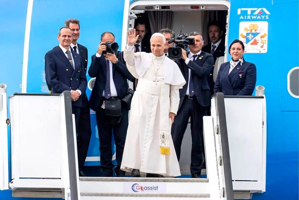 El papa León XIV saluda al descender de un avión.