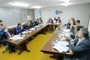 Concejales del Concejo Deliberante de Tafí Viejo levantan la mano durante una votación en la sesión ordinaria, en torno a la mesa del recinto.