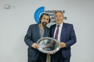 El músico Quique Yance sostiene una placa de reconocimiento junto al concejal Jorge Llarrull en el Concejo Deliberante de Tafí Viejo.