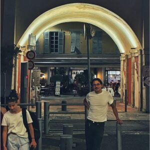 Facundo Benero junto a un arco iluminado de noche, con persianas y un restaurante al fondo